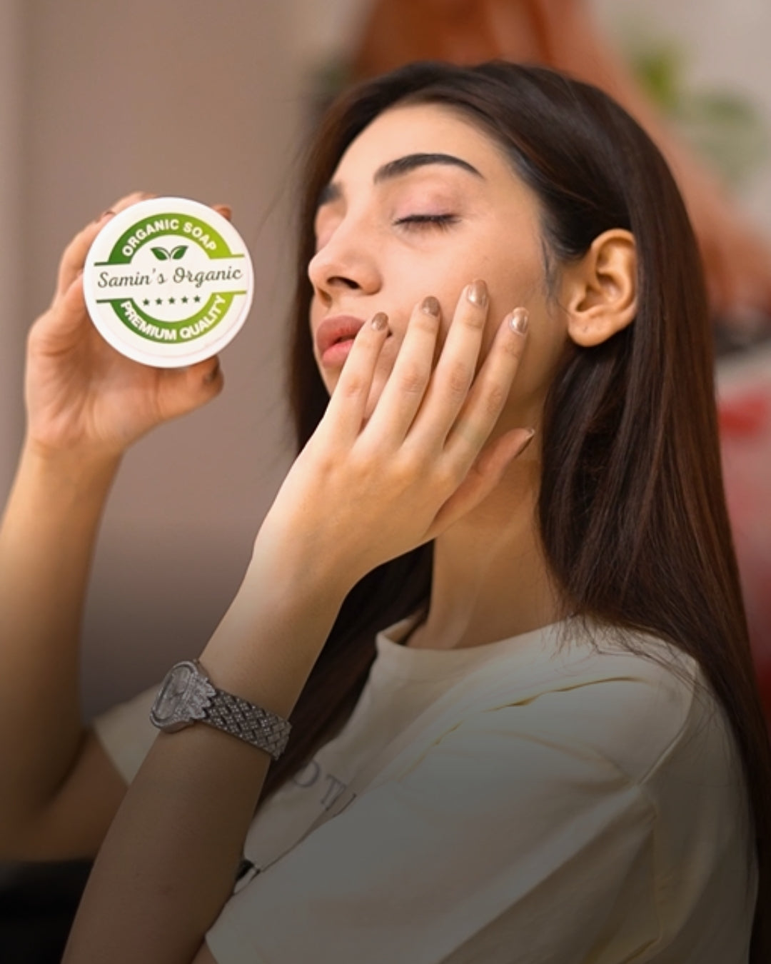 Woman applying cream to her face with a container labeled 'Samin's Organic' in the foreground.